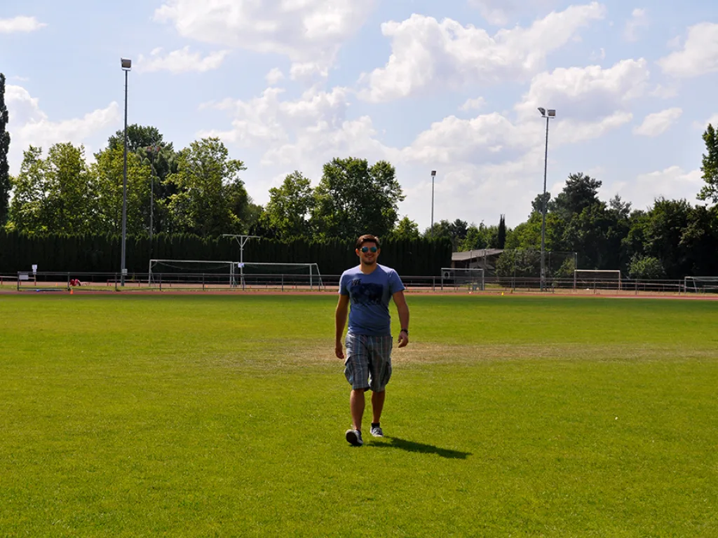 Person steht allein auf dem Rasenplatz.